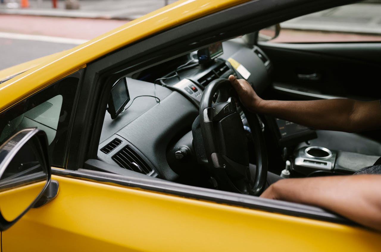 services-03 From above of crop anonymous male ethnic driver driving taxi car with device providing information along route